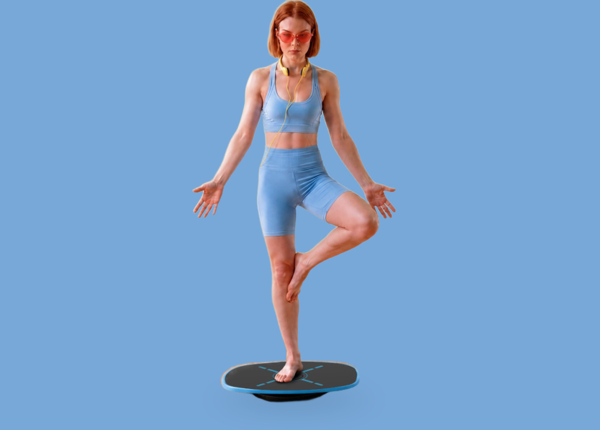 A woman holding a one-leg balance on the GoBalance Sport board