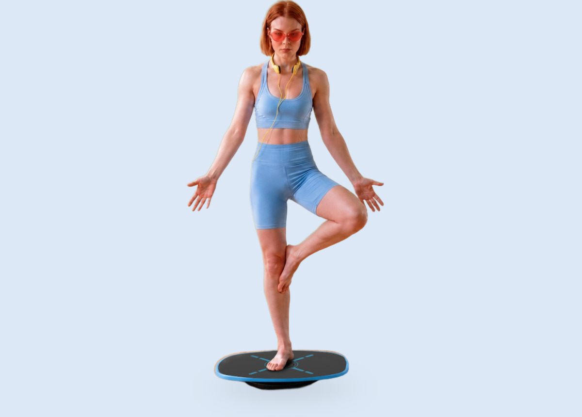 A woman holding a one-leg balance on the GoBalance Sport board